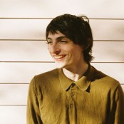 Boy smiling in green shirt against wall